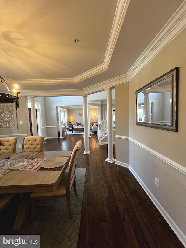 unfurnished dining area with decorative columns, ornamental molding, a raised ceiling, and dark wood-type flooring