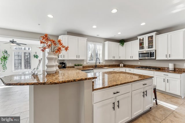 kitchen featuring sink, appliances with stainless steel finishes, dark stone counters, and a kitchen island