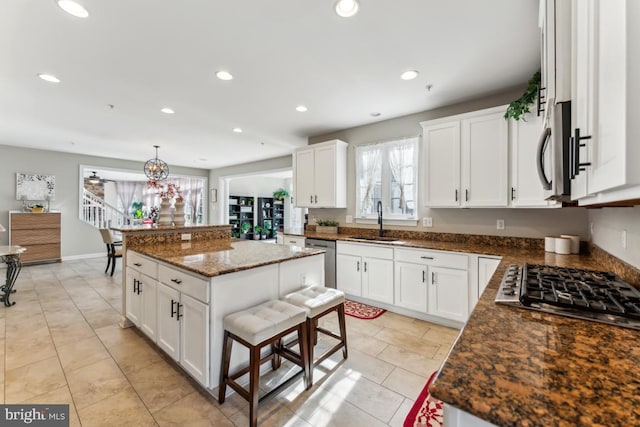 kitchen with sink, white cabinetry, appliances with stainless steel finishes, a kitchen island, and pendant lighting