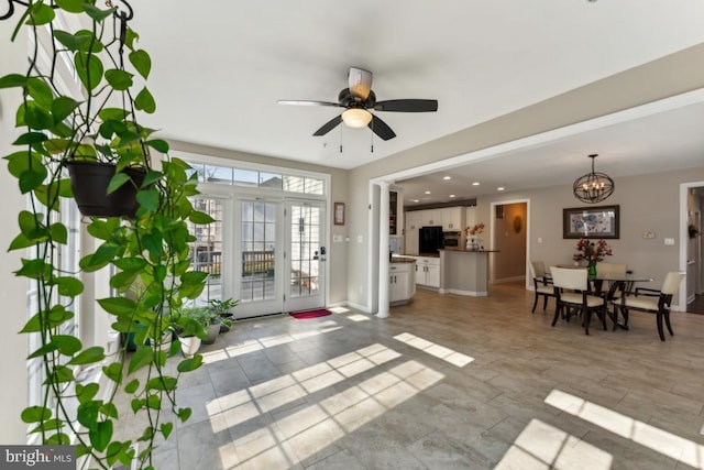 interior space featuring ceiling fan with notable chandelier