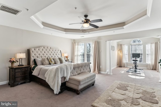 carpeted bedroom with a tray ceiling and decorative columns