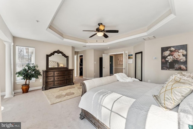 bedroom featuring ceiling fan, a spacious closet, light colored carpet, a raised ceiling, and ornate columns