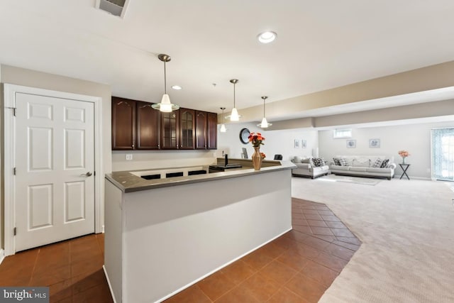 kitchen featuring hanging light fixtures, dark brown cabinets, and dark colored carpet