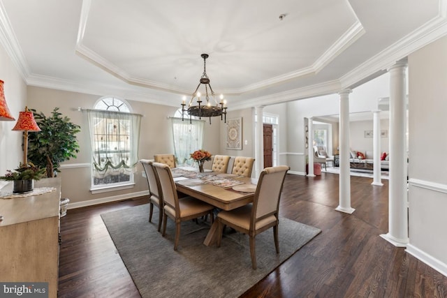 dining room with ornate columns, crown molding, an inviting chandelier, a tray ceiling, and dark hardwood / wood-style flooring