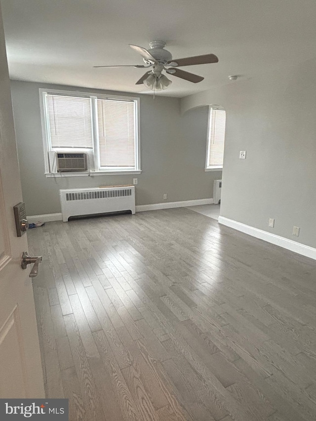 unfurnished room with cooling unit, ceiling fan, radiator heating unit, and hardwood / wood-style floors