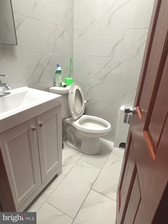 bathroom with vanity, radiator, tile walls, and toilet