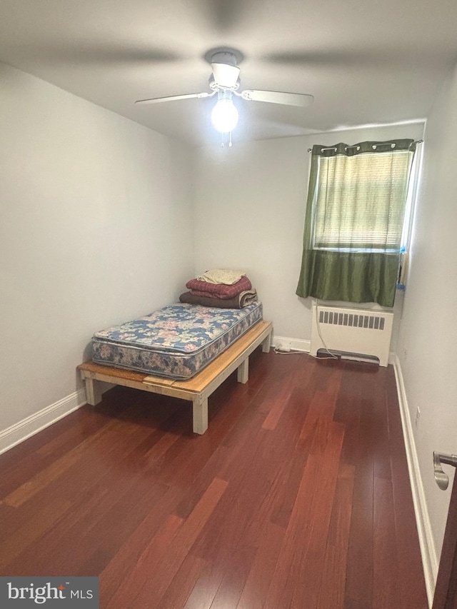 bedroom with dark hardwood / wood-style flooring, radiator, and ceiling fan