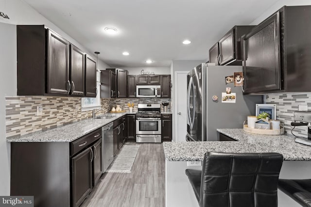 kitchen with a breakfast bar, decorative light fixtures, sink, backsplash, and stainless steel appliances