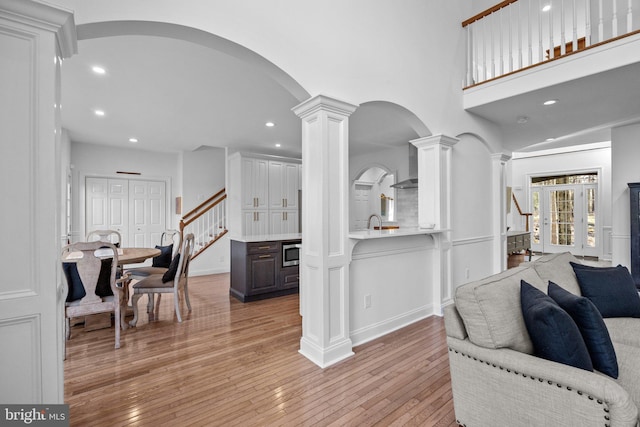 living room featuring ornate columns, a towering ceiling, and light hardwood / wood-style floors