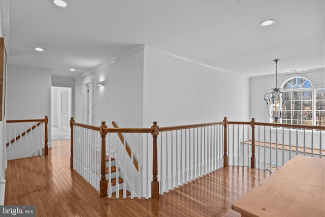 corridor featuring wood-type flooring, crown molding, and a chandelier