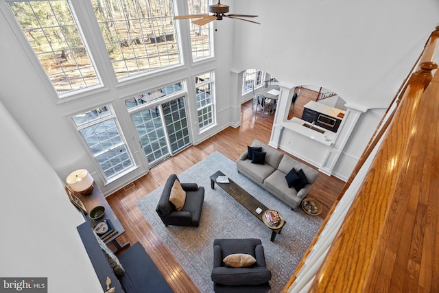 living room with a towering ceiling, plenty of natural light, decorative columns, and hardwood / wood-style flooring