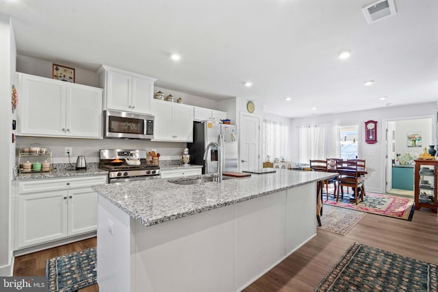 kitchen featuring sink, a center island with sink, appliances with stainless steel finishes, dark hardwood / wood-style floors, and white cabinets