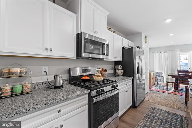 kitchen featuring light stone counters, stainless steel appliances, dark wood-type flooring, and white cabinets