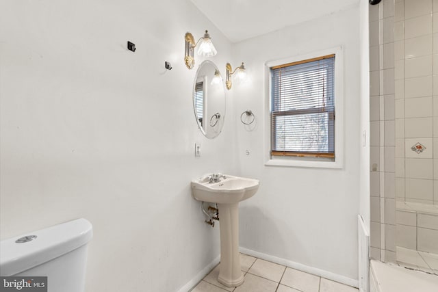 bathroom featuring tile patterned flooring, a tile shower, and toilet