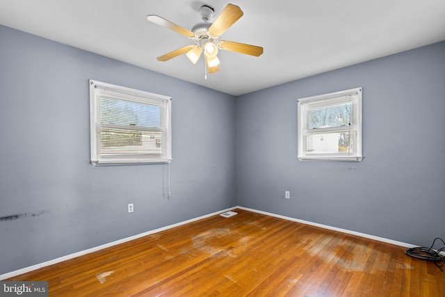 unfurnished room with ceiling fan, hardwood / wood-style flooring, and a healthy amount of sunlight