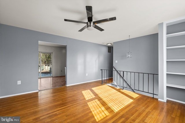 spare room featuring hardwood / wood-style flooring and ceiling fan with notable chandelier