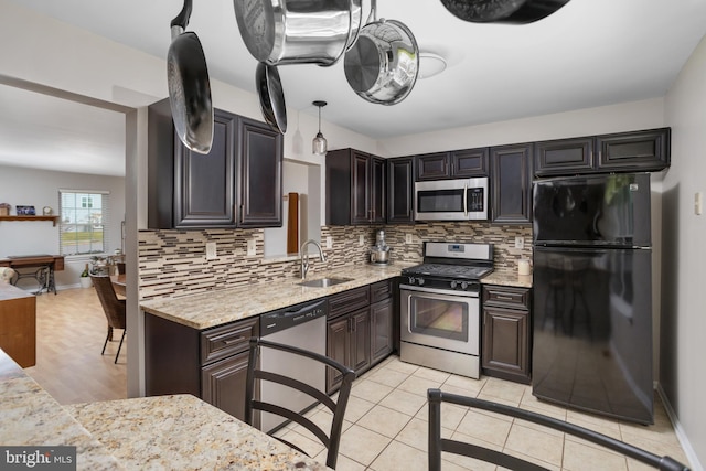 kitchen featuring dark brown cabinetry, sink, decorative backsplash, and stainless steel appliances