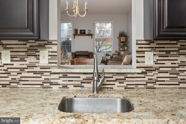 kitchen with an inviting chandelier, sink, decorative backsplash, and dark brown cabinets