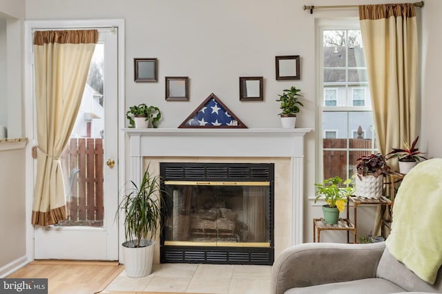 sitting room with a tile fireplace and light wood-type flooring