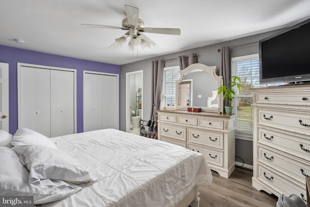 bedroom featuring ceiling fan, light hardwood / wood-style floors, and two closets