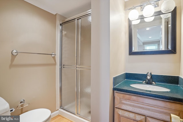 bathroom with toilet, vanity, crown molding, and a shower with shower door