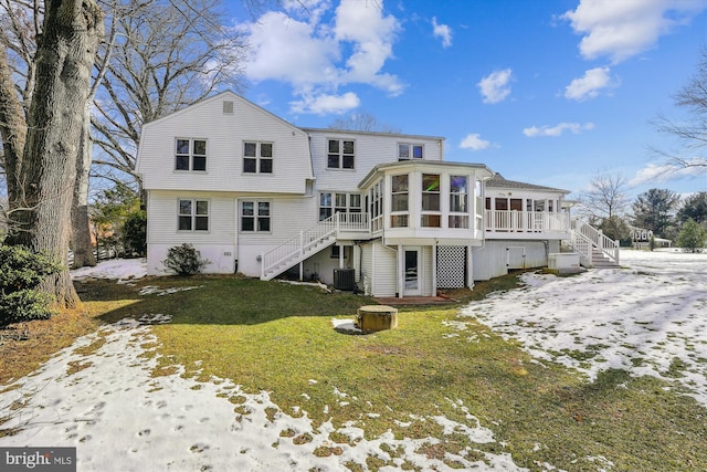 snow covered house featuring central AC, a sunroom, and a lawn