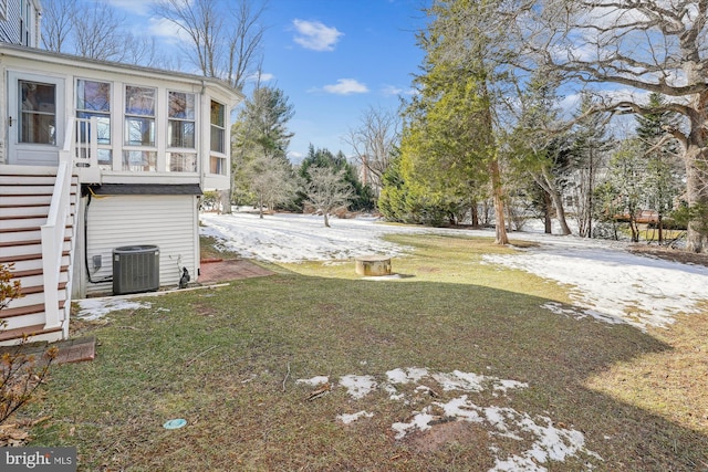 snowy yard with a sunroom and central AC unit