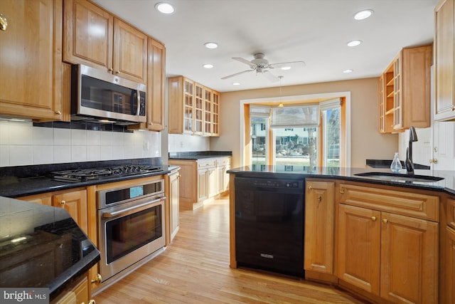 kitchen with sink, tasteful backsplash, light wood-type flooring, ceiling fan, and black appliances