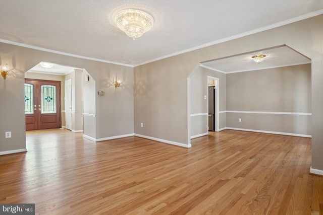 spare room with crown molding, a chandelier, light hardwood / wood-style floors, and french doors