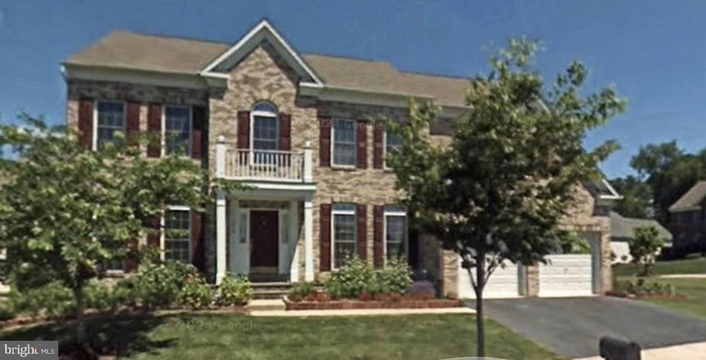 view of front of house with a balcony, driveway, a garage, and a front lawn