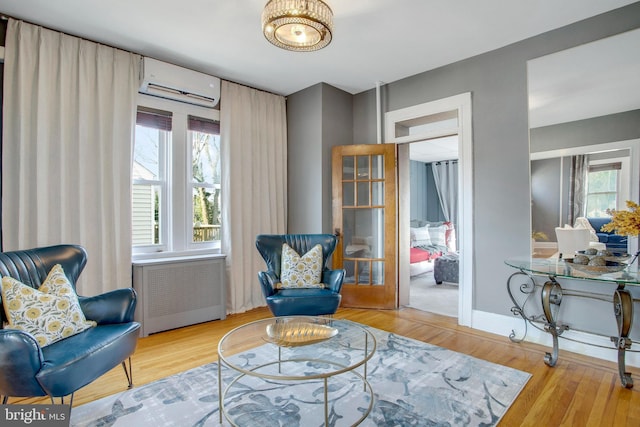 sitting room featuring radiator, hardwood / wood-style flooring, and an AC wall unit