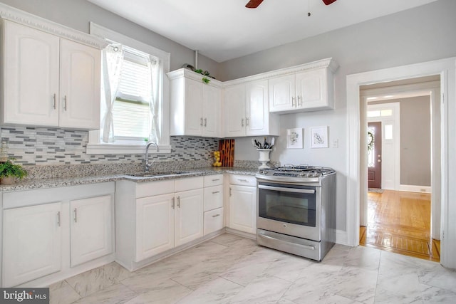 kitchen with tasteful backsplash, sink, stainless steel range with gas stovetop, and white cabinets