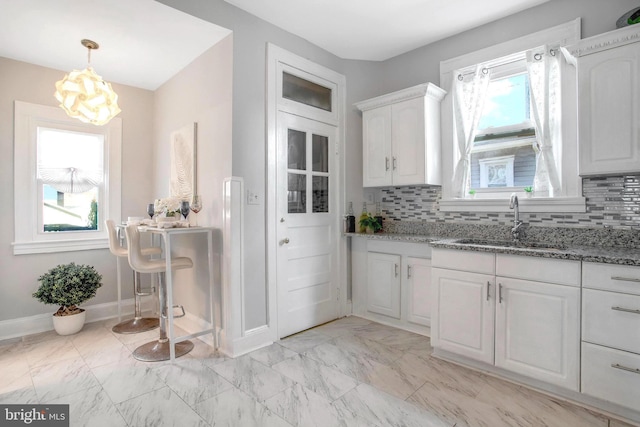 kitchen featuring white cabinetry, a healthy amount of sunlight, sink, and tasteful backsplash