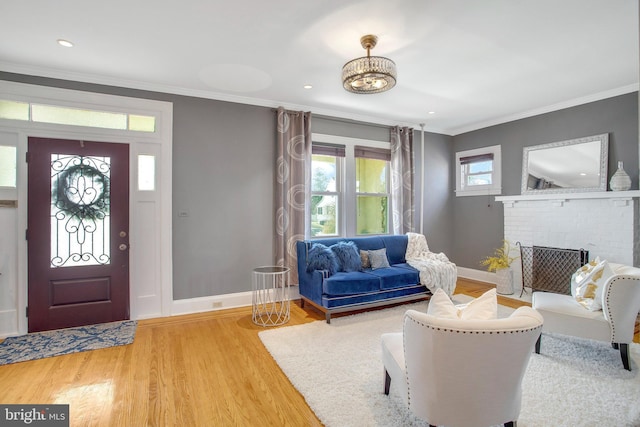 entryway with ornamental molding, wood-type flooring, and a fireplace