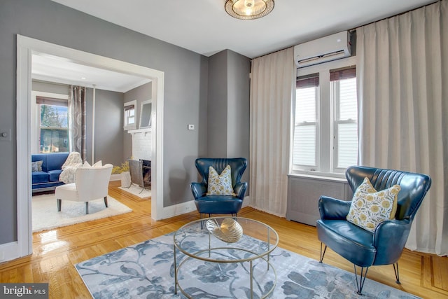 sitting room featuring hardwood / wood-style floors, radiator heating unit, a wall mounted AC, and a brick fireplace