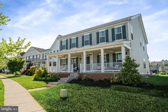 colonial house featuring covered porch, ceiling fan, and a front yard