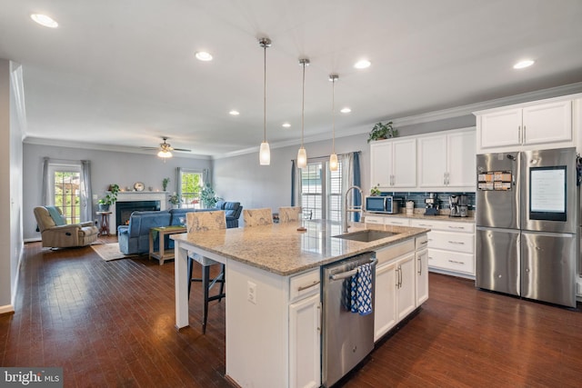 kitchen with ornamental molding, open floor plan, a breakfast bar area, a sink, and stainless steel appliances