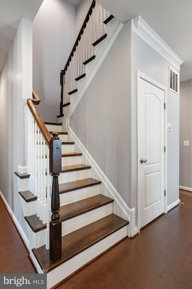 staircase featuring visible vents, wood-type flooring, and baseboards