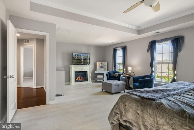 bedroom with crown molding, a glass covered fireplace, wood finished floors, and visible vents
