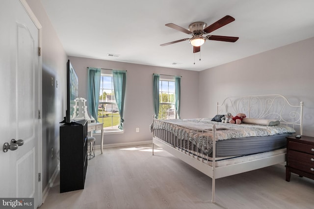 bedroom with light wood-style floors, baseboards, ceiling fan, and visible vents
