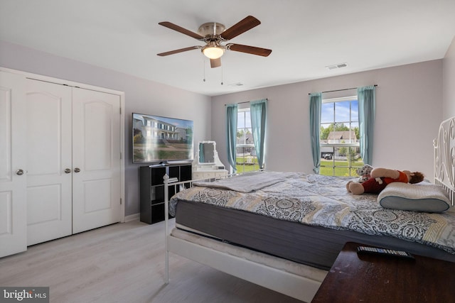 bedroom featuring visible vents, light wood-style flooring, ceiling fan, and a closet