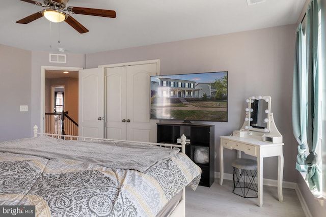 bedroom featuring ceiling fan, light wood finished floors, baseboards, visible vents, and a closet