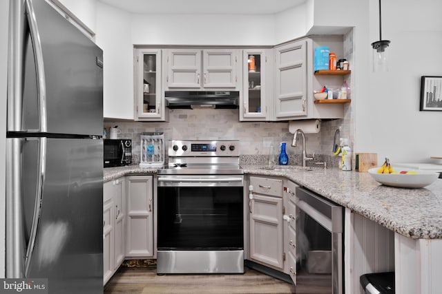 kitchen featuring sink, light stone counters, decorative light fixtures, stainless steel appliances, and white cabinets