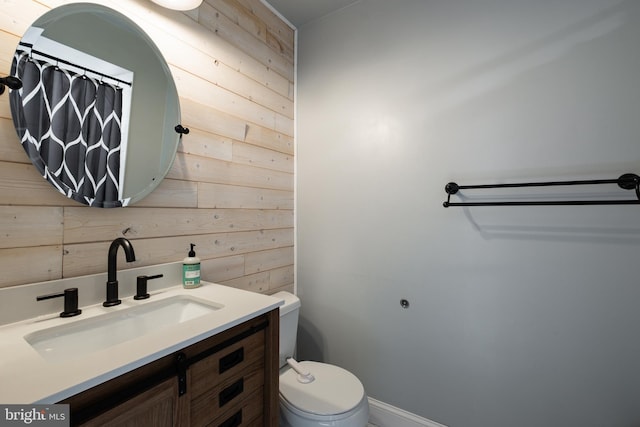 bathroom with vanity, wooden walls, and toilet