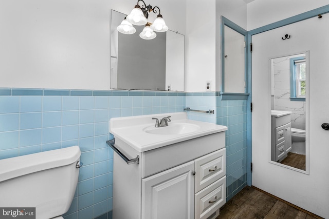 bathroom with vanity, toilet, hardwood / wood-style floors, and tile walls