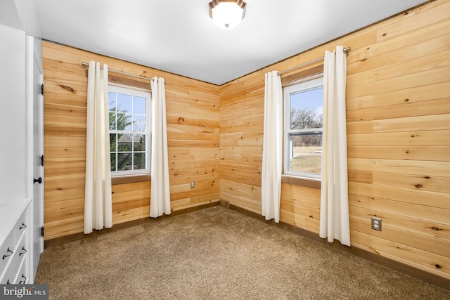 carpeted spare room with wooden walls