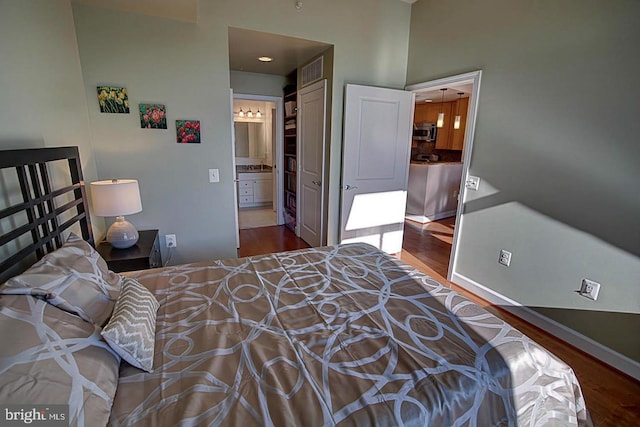 bedroom featuring ensuite bath and hardwood / wood-style floors