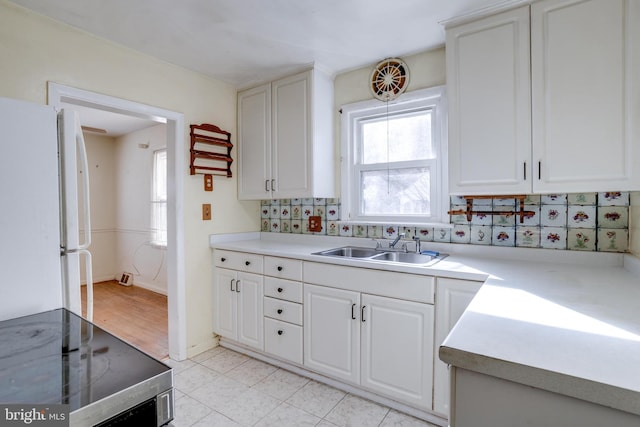 kitchen featuring sink, white cabinetry, electric range, white refrigerator, and backsplash