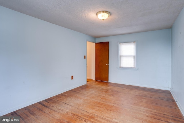 unfurnished room featuring light hardwood / wood-style floors and a textured ceiling