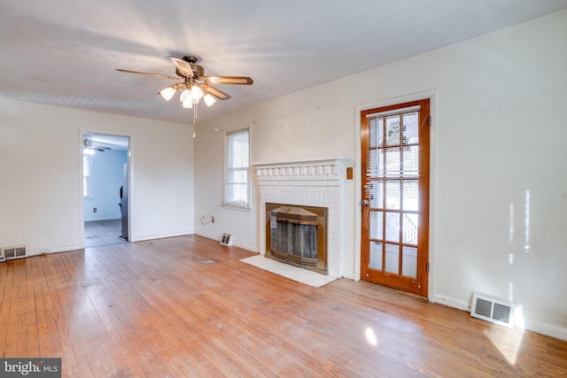 unfurnished living room with ceiling fan, light hardwood / wood-style floors, and a brick fireplace